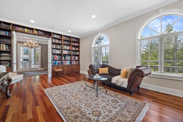 living area with built in shelves, crown molding, dark wood-type flooring, and a chandelier