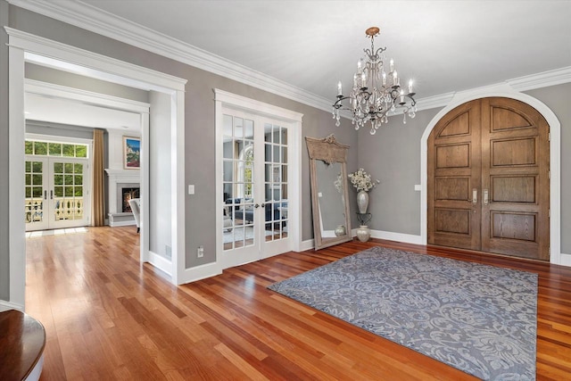 entrance foyer with hardwood / wood-style flooring, a chandelier, crown molding, and french doors