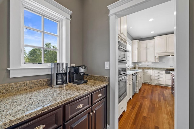 kitchen featuring dark brown cabinetry, light stone counters, tasteful backsplash, dark hardwood / wood-style flooring, and white cabinetry