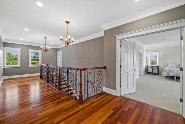 hall with hardwood / wood-style floors, a wealth of natural light, and an inviting chandelier