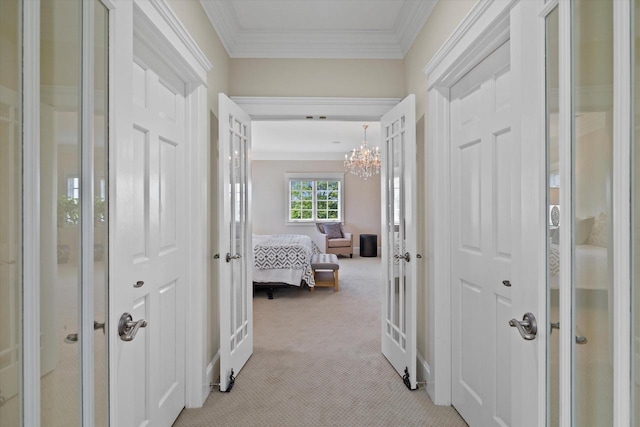 corridor featuring light carpet, ornamental molding, and a notable chandelier