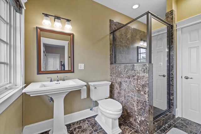 bathroom featuring a shower with door and toilet