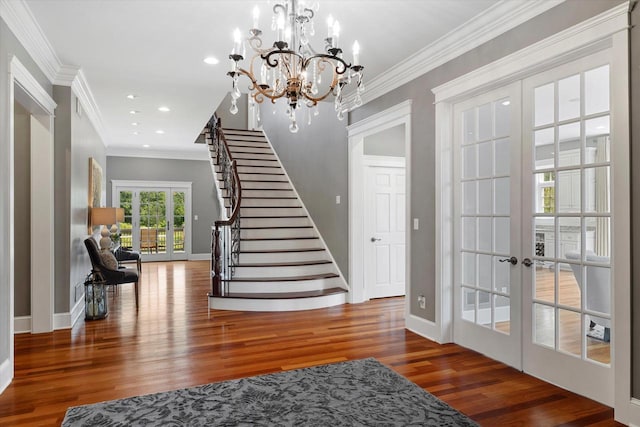 foyer entrance featuring dark hardwood / wood-style flooring, french doors, a notable chandelier, and ornamental molding