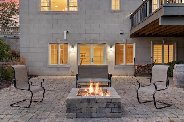 patio terrace at dusk with a fire pit and a balcony