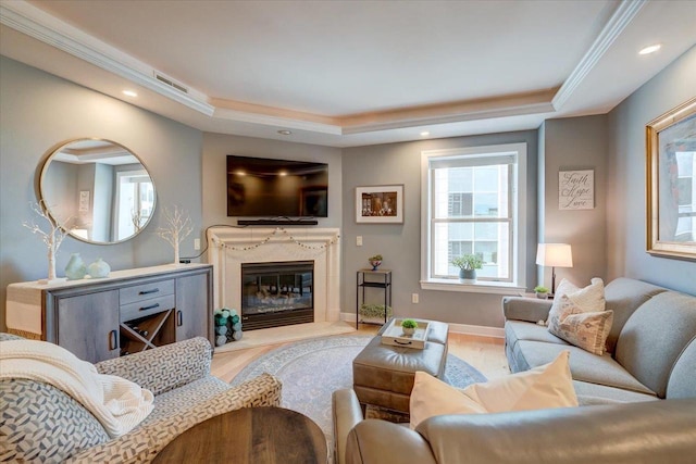 living room featuring a tray ceiling, light hardwood / wood-style flooring, and a high end fireplace