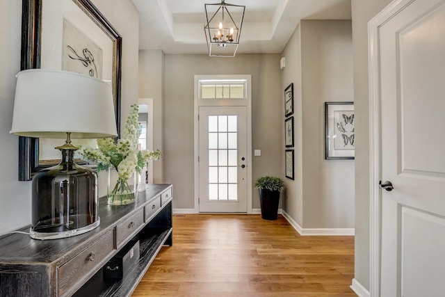 interior space featuring a tray ceiling, light hardwood / wood-style flooring, and a notable chandelier