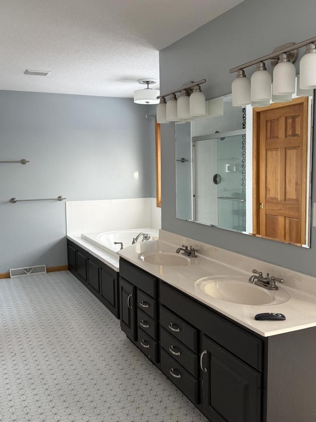 bathroom featuring vanity, separate shower and tub, and a textured ceiling