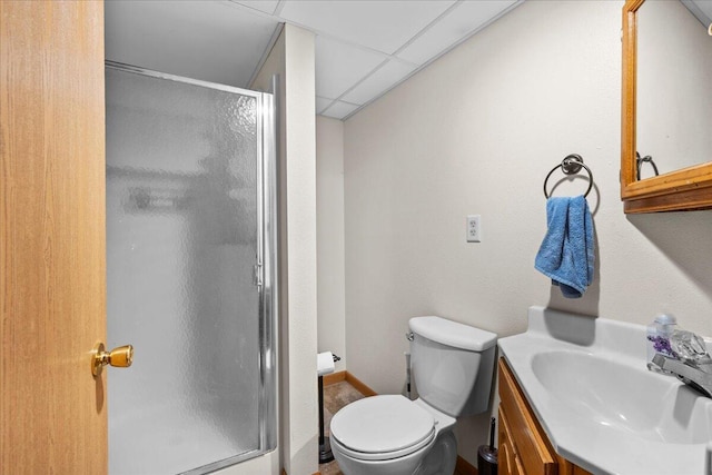 bathroom with a paneled ceiling, vanity, toilet, and a shower with shower door