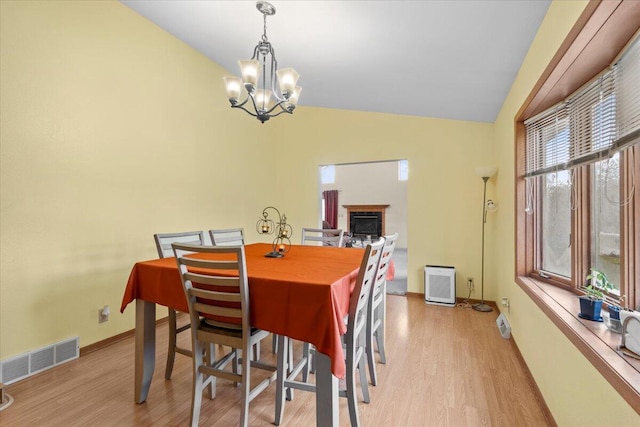 dining room with vaulted ceiling, light wood-type flooring, and an inviting chandelier