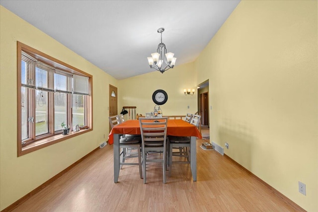 dining room featuring a chandelier, vaulted ceiling, and light hardwood / wood-style flooring