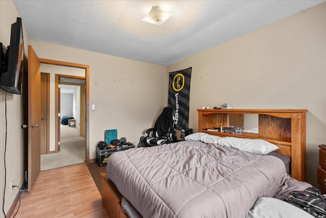 bedroom featuring a textured ceiling and light hardwood / wood-style floors