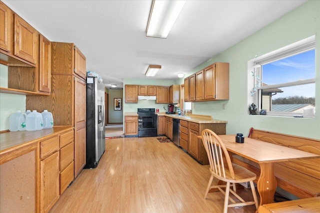 kitchen featuring sink, stainless steel fridge with ice dispenser, light hardwood / wood-style flooring, black electric range oven, and dishwashing machine