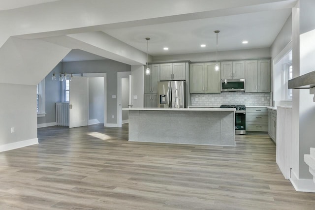 kitchen with gray cabinetry, pendant lighting, a kitchen island, and stainless steel appliances