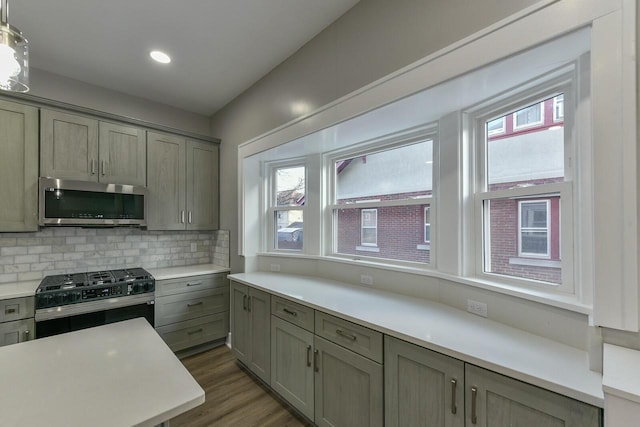 kitchen featuring appliances with stainless steel finishes, backsplash, dark hardwood / wood-style floors, and hanging light fixtures