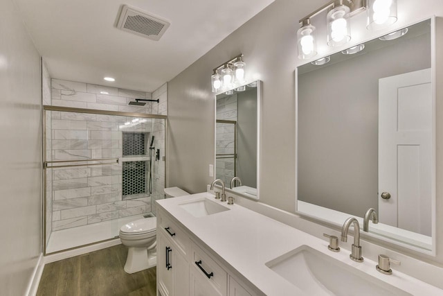 bathroom with toilet, a shower with door, vanity, and hardwood / wood-style flooring