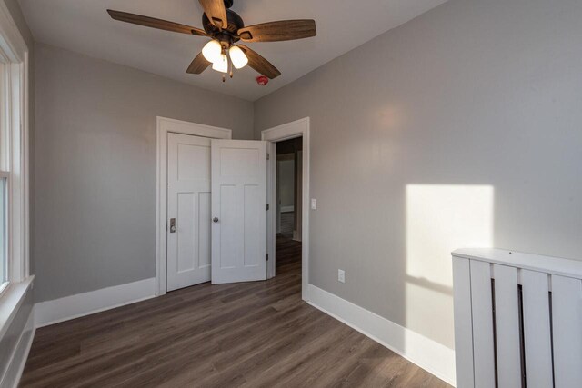 unfurnished bedroom with dark hardwood / wood-style flooring, a closet, and ceiling fan