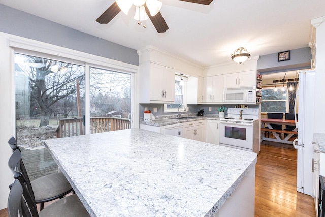 kitchen with white appliances, white cabinets, sink, light hardwood / wood-style flooring, and ceiling fan