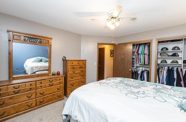 carpeted bedroom with ceiling fan and two closets