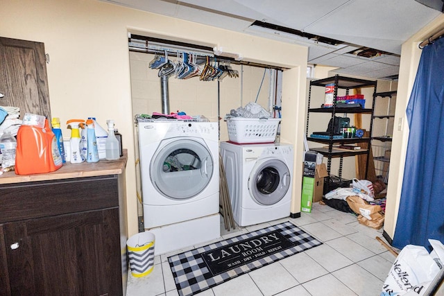 clothes washing area with light tile patterned floors and washer and dryer