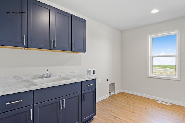 laundry room with cabinets, hookup for a washing machine, electric dryer hookup, sink, and light hardwood / wood-style floors