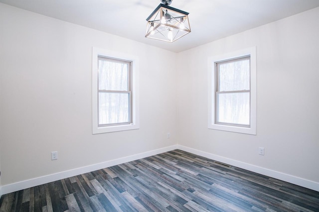 unfurnished room with dark hardwood / wood-style flooring, a wealth of natural light, and a chandelier