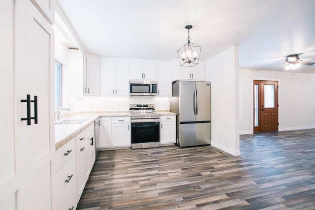 kitchen with ceiling fan with notable chandelier, stainless steel appliances, sink, white cabinetry, and hanging light fixtures