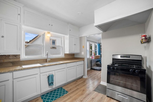 kitchen with sink, light hardwood / wood-style flooring, white cabinetry, and stainless steel gas range