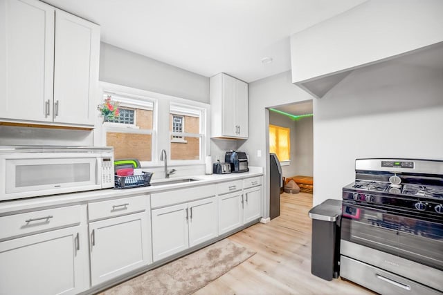 kitchen with gas range, light wood-type flooring, white cabinetry, and sink