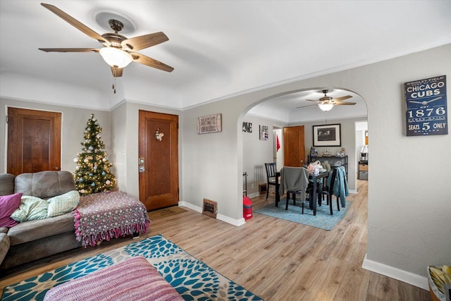 living room featuring light hardwood / wood-style floors, ceiling fan, and ornamental molding