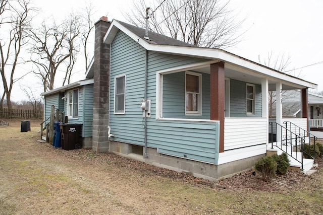 view of side of home featuring a lawn and covered porch