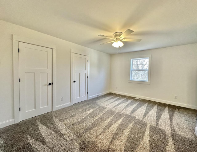 unfurnished bedroom with multiple closets, ceiling fan, and carpet floors