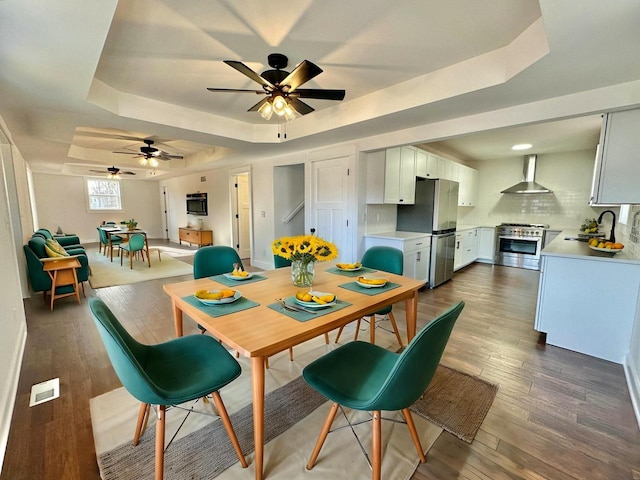 dining area featuring dark hardwood / wood-style flooring, a tray ceiling, ceiling fan, and sink