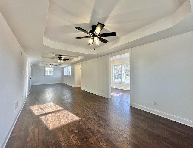 empty room featuring ceiling fan, a wealth of natural light, and a tray ceiling