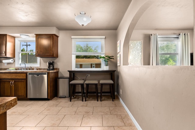 kitchen featuring dishwasher, light tile patterned floors, a wealth of natural light, and sink