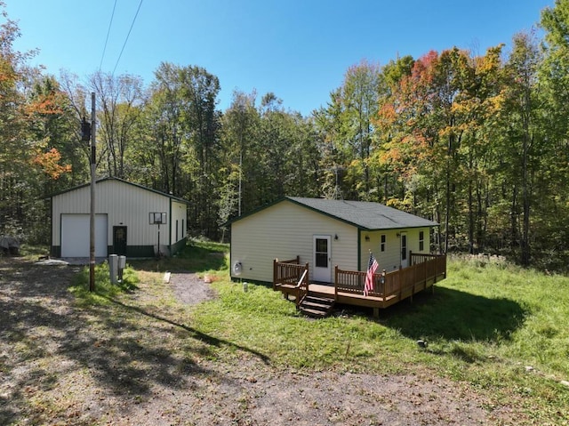 rear view of property with a deck, a garage, and an outdoor structure