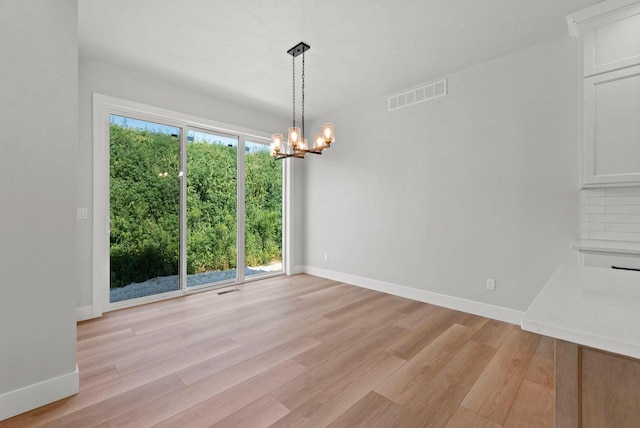 unfurnished dining area with light hardwood / wood-style floors and an inviting chandelier