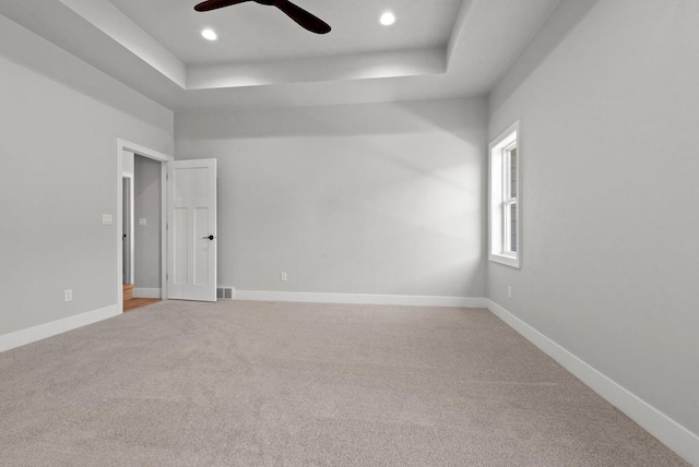 unfurnished room featuring carpet flooring, a raised ceiling, and ceiling fan