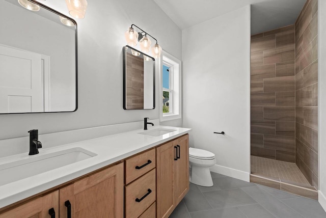 bathroom featuring tile patterned flooring, a tile shower, vanity, and toilet