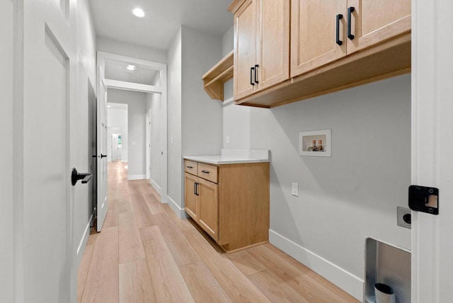 clothes washing area featuring hookup for a washing machine, light hardwood / wood-style flooring, cabinets, and hookup for an electric dryer