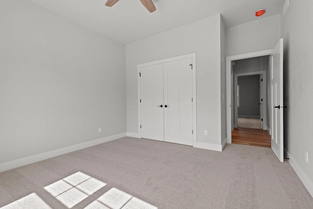 unfurnished bedroom featuring ceiling fan, light colored carpet, and a closet