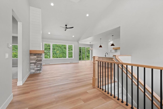 hallway with light hardwood / wood-style floors, high vaulted ceiling, and sink