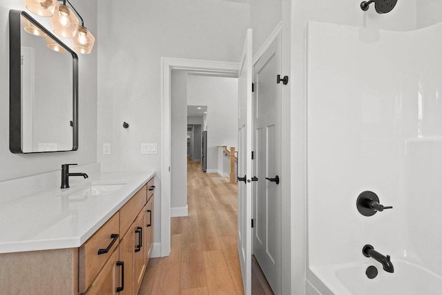 bathroom with hardwood / wood-style floors, vanity, and washtub / shower combination