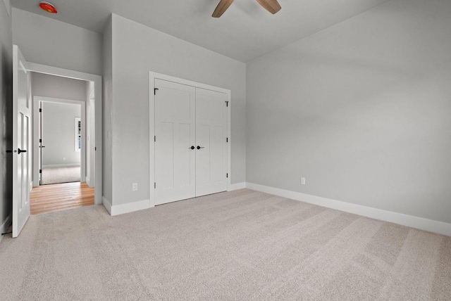 unfurnished bedroom with ceiling fan, a closet, and light carpet