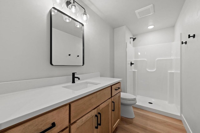 bathroom featuring wood-type flooring, vanity, toilet, and walk in shower