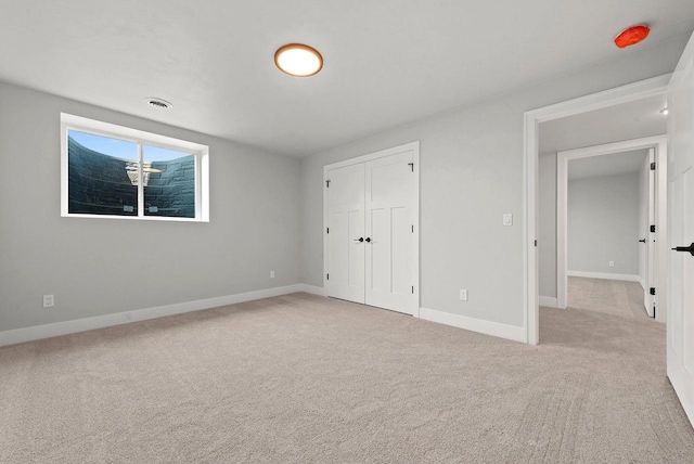 unfurnished bedroom featuring light carpet and a closet