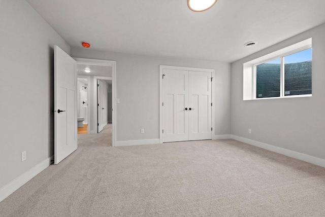 unfurnished bedroom with light colored carpet and a closet