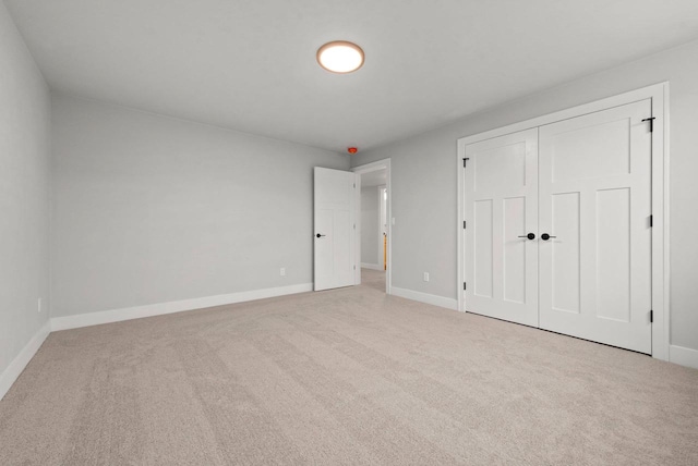 unfurnished bedroom with light colored carpet and a closet