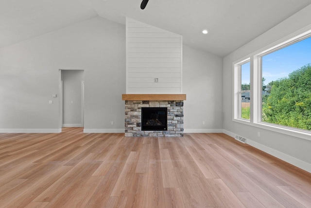 unfurnished living room featuring a stone fireplace, light wood-type flooring, and vaulted ceiling