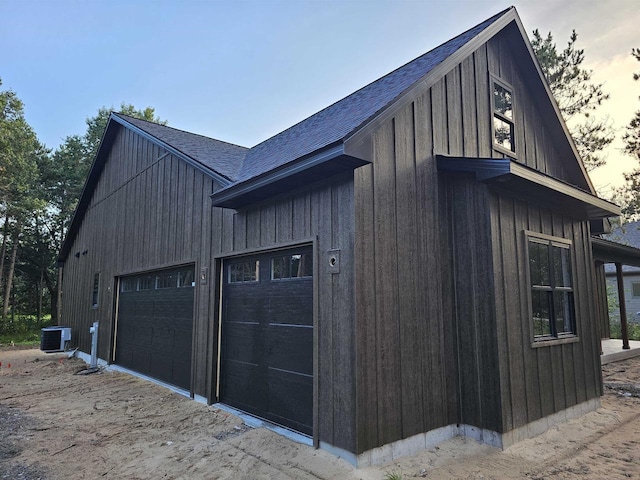 property exterior at dusk featuring central AC and a garage