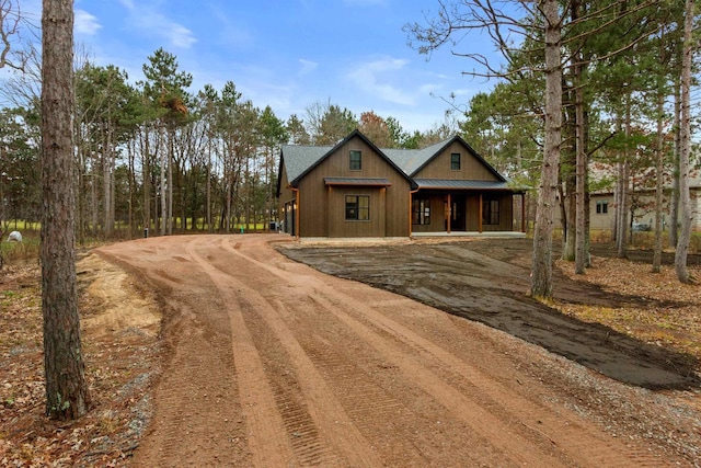 view of front facade with metal roof, driveway, and a standing seam roof